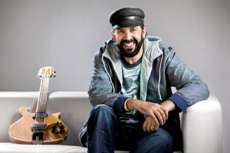 Juan Luis Guerra sitting on couch and guitar next to him